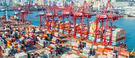 Container port operating with automated cranes and docked vessel.